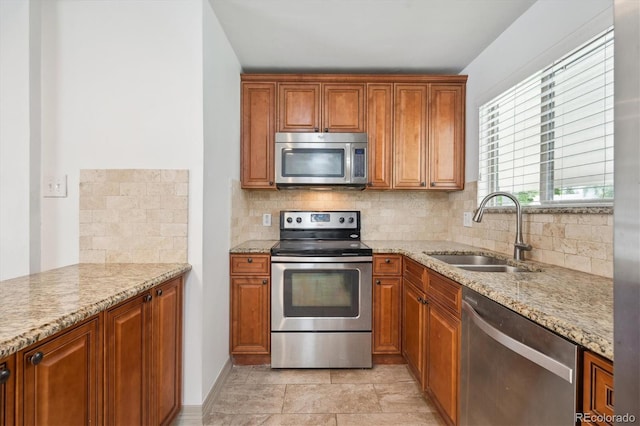 1420 S Leyden St, Denver, CO 80224 - kitchen with appliances with stainless steel finishes, a sink, decorative backsplash, light stone counters, and brown cabinetry
