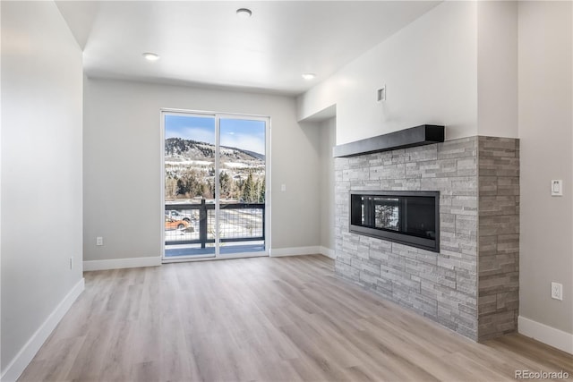 unfurnished living room featuring a mountain view, a fireplace, and light hardwood / wood-style floors