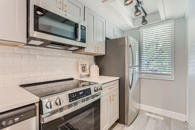 kitchen featuring appliances with stainless steel finishes, backsplash, white cabinetry, and light hardwood / wood-style flooring