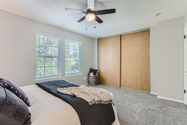 carpeted bedroom with a textured ceiling, ceiling fan, and a closet