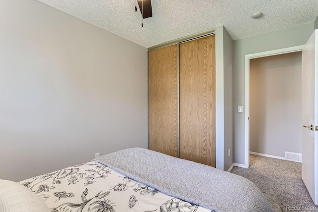 bedroom with a closet, ceiling fan, a textured ceiling, and carpet floors