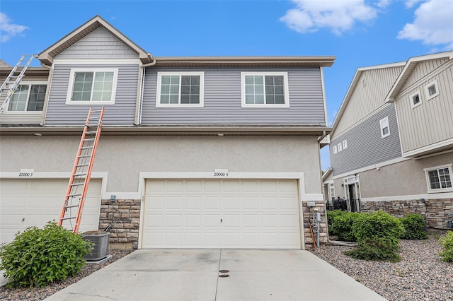 20000 E 40th Ave Unit 4, Denver, CO 80249 - view of front of property featuring stone siding, a garage, driveway, and stucco siding