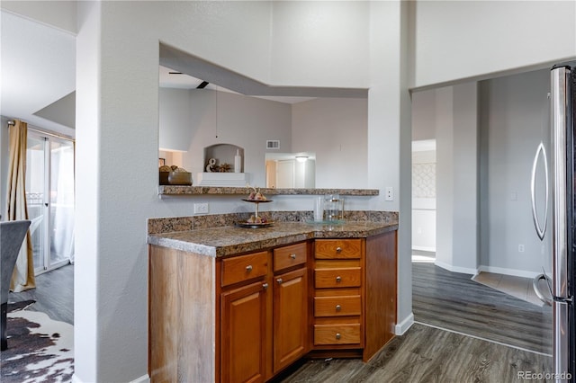 kitchen with dark hardwood / wood-style flooring, kitchen peninsula, and stainless steel refrigerator