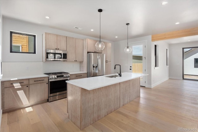 126 Chase St, Salida, CO 81201 - kitchen featuring stainless steel appliances, light brown cabinets, a sink, light wood-type flooring, and a kitchen island with sink