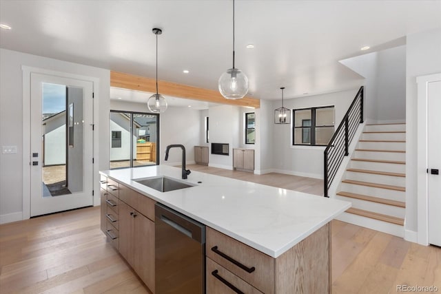 126 Chase St, Salida, CO 81201 - kitchen featuring stainless steel dishwasher, a sink, light wood-style flooring, an island with sink, and light brown cabinetry