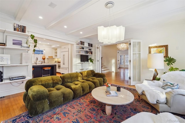 living room featuring hardwood / wood-style flooring, ornamental molding, beam ceiling, and a notable chandelier