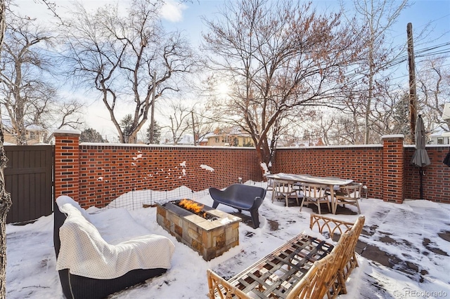 snow covered patio with an outdoor fire pit