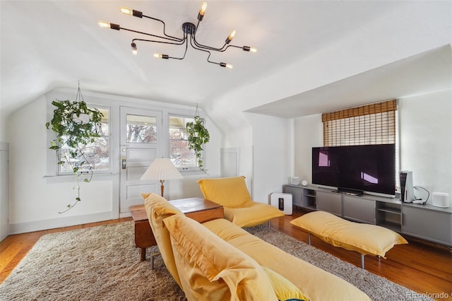 living room with wood-type flooring, lofted ceiling, and an inviting chandelier