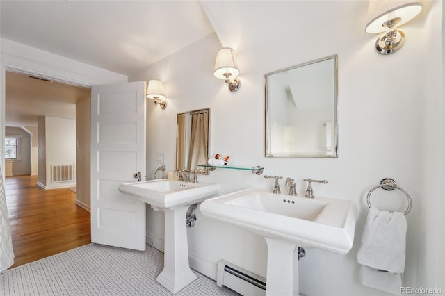 bathroom featuring dual sinks, baseboard heating, and tile patterned floors