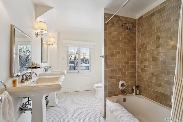 bathroom with tiled shower / bath combo, plenty of natural light, toilet, and tile patterned floors