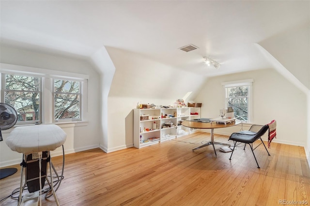 home office with light hardwood / wood-style floors, vaulted ceiling, and plenty of natural light