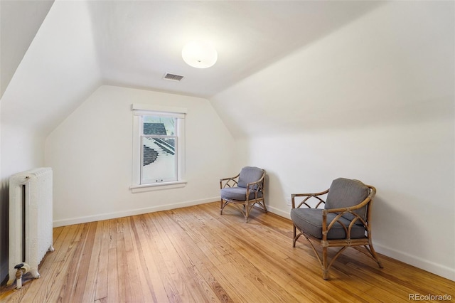 bonus room with radiator, lofted ceiling, and light wood-type flooring