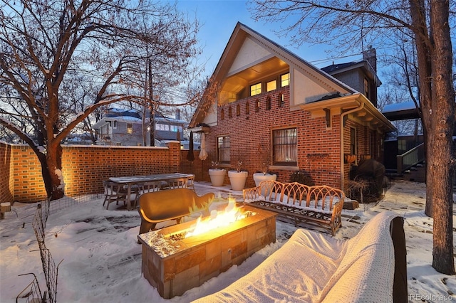 snow covered rear of property featuring a fire pit