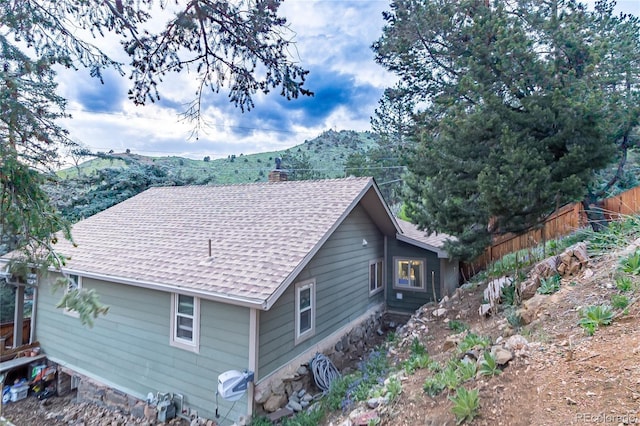 2795 SE Grapevine Rd, Idledale, CO 80453 - view of home's exterior featuring roof with shingles, fence, a chimney, and a mountain view