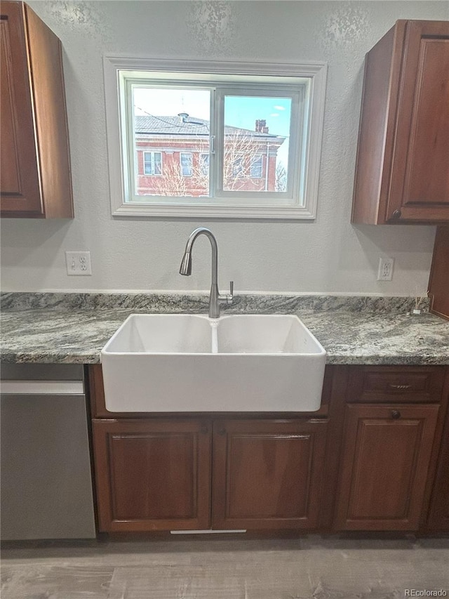 kitchen with sink, stainless steel dishwasher, and light stone counters