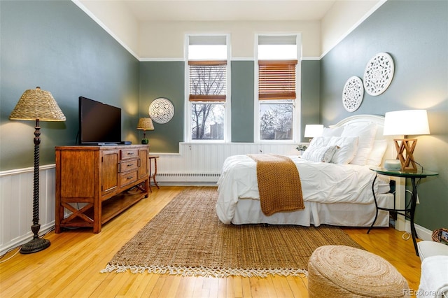 1140 Columbine St Unit 302, Denver, CO 80206 - bedroom featuring a baseboard heating unit, light wood-type flooring, and a wainscoted wall