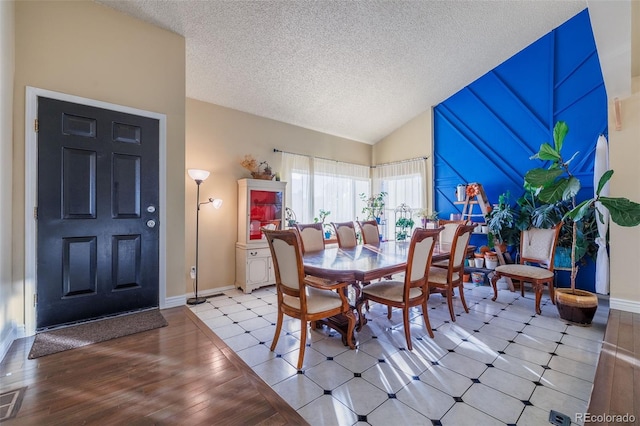 dining area with baseboards, a textured ceiling, wood finished floors, and vaulted ceiling