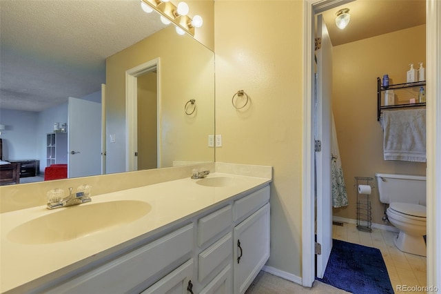 full bath with a sink, toilet, double vanity, and a textured ceiling