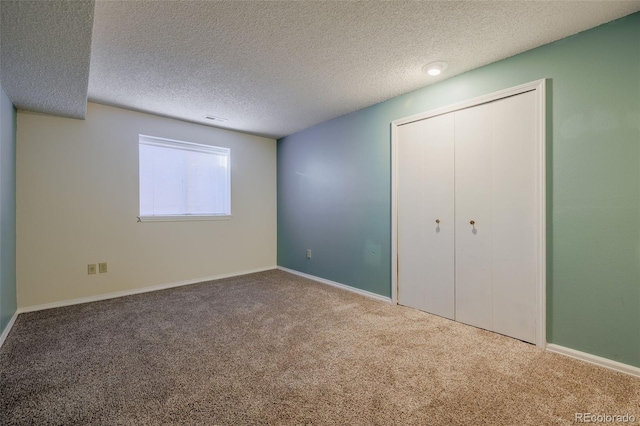 unfurnished bedroom with visible vents, baseboards, carpet, a closet, and a textured ceiling