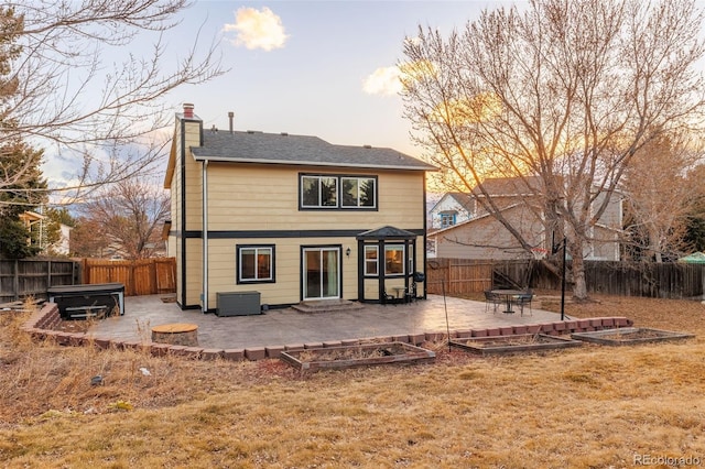 back of property at dusk with a patio, a lawn, a fenced backyard, and a chimney