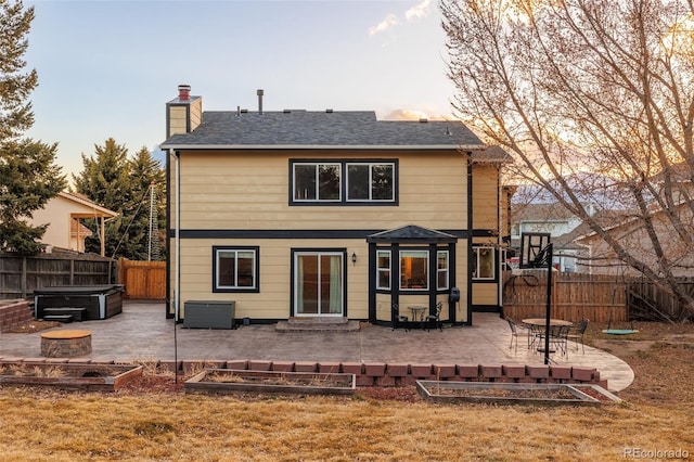 back of house at dusk featuring a patio, cooling unit, a garden, a fenced backyard, and a chimney