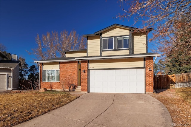 traditional-style house featuring brick siding, concrete driveway, a garage, and fence