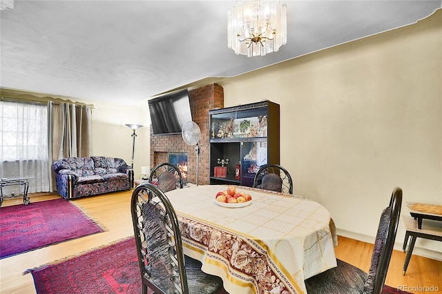 4705 Upham St, Wheat Ridge, CO 80033 - dining space with a chandelier, wood finished floors, and a brick fireplace
