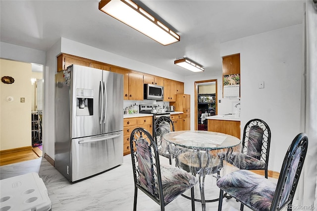 4705 Upham St, Wheat Ridge, CO 80033 - kitchen with stainless steel appliances, light countertops, brown cabinets, light marble finish flooring, and decorative backsplash