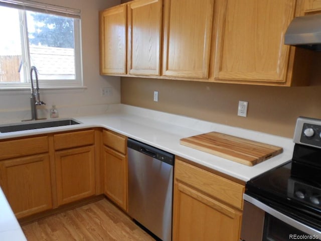 kitchen with stainless steel appliances, sink, and light hardwood / wood-style flooring