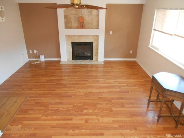 unfurnished living room with ceiling fan, a high end fireplace, and light hardwood / wood-style flooring