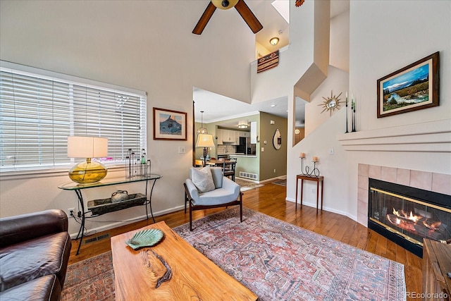 10389 W Fair Ave Unit E, Littleton, CO 80127 - living room with a ceiling fan, wood finished floors, a fireplace, baseboards, and a towering ceiling
