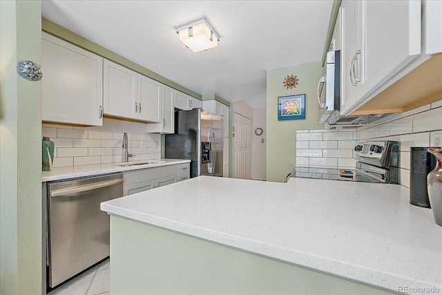 10389 W Fair Ave Unit E, Littleton, CO 80127 - kitchen with stainless steel appliances, a sink, tasteful backsplash, a peninsula, and white cabinetry