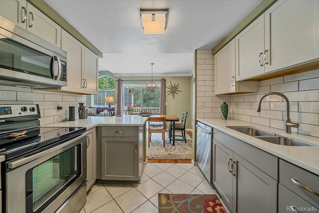 10389 W Fair Ave Unit E, Littleton, CO 80127 - kitchen with stainless steel appliances, gray cabinets, a sink, light tile patterned floors, and a textured ceiling