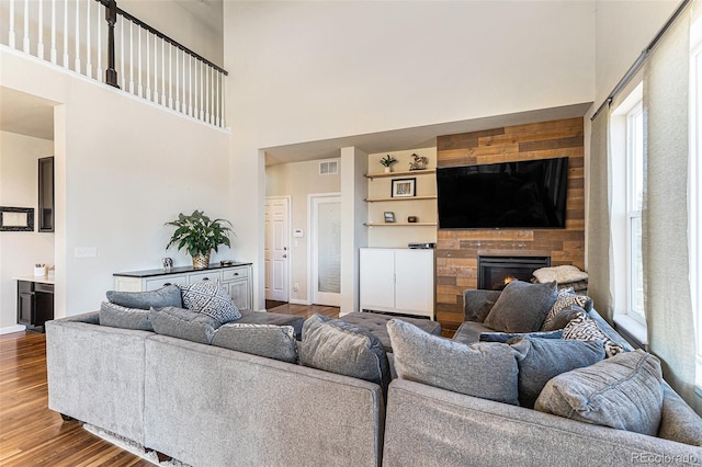 living room with a fireplace, visible vents, a high ceiling, wood finished floors, and baseboards