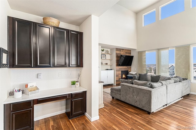 living area with a healthy amount of sunlight, built in study area, a fireplace, and wood finished floors