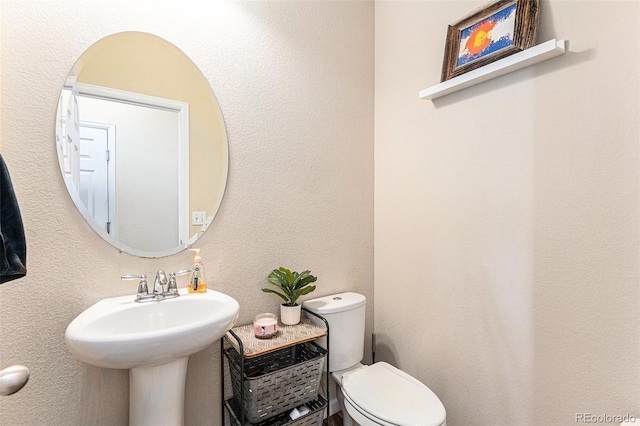 bathroom featuring toilet and a textured wall