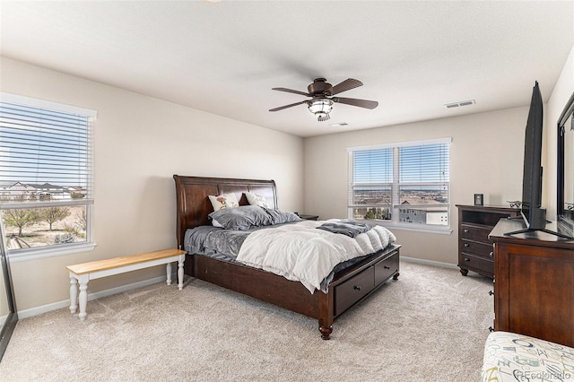 bedroom with visible vents, light colored carpet, baseboards, and ceiling fan