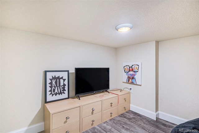 living area with baseboards, wood finished floors, and a textured ceiling