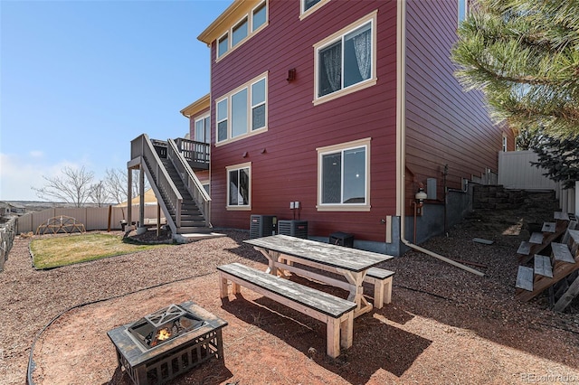 back of property featuring an outdoor fire pit, fence, a deck, and stairs