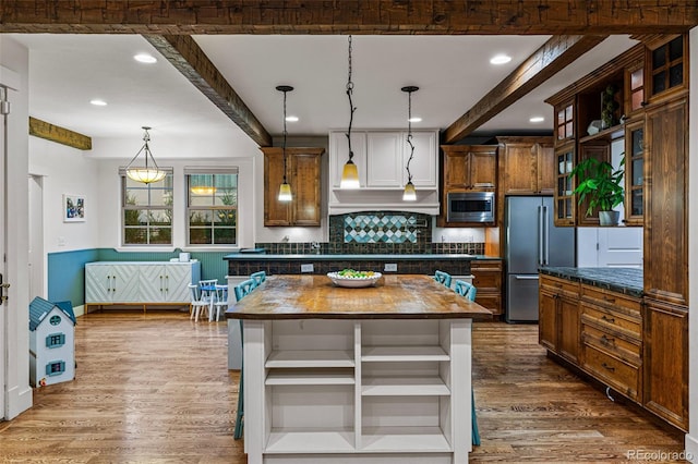 kitchen featuring decorative backsplash, pendant lighting, stainless steel appliances, and beam ceiling