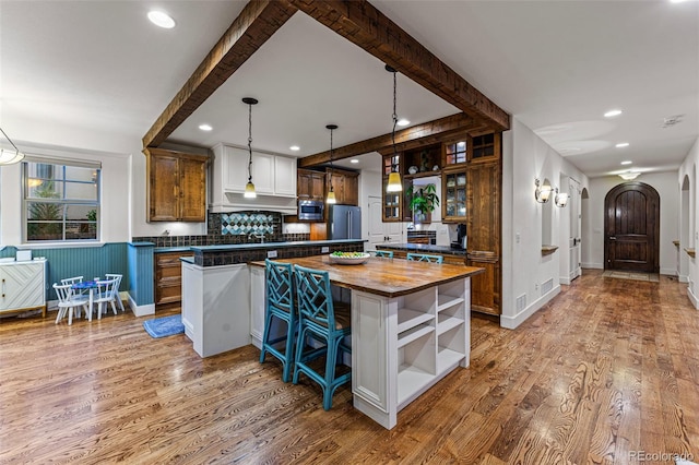 kitchen featuring appliances with stainless steel finishes, a center island, wood counters, wood-type flooring, and hanging light fixtures