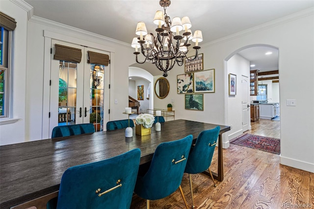 dining space with hardwood / wood-style flooring, french doors, a wealth of natural light, and ornamental molding