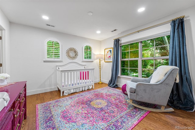 bedroom featuring a nursery area and hardwood / wood-style floors