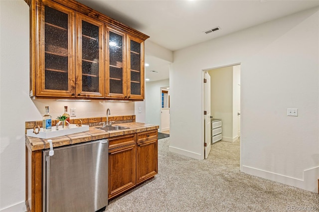 kitchen featuring sink, dishwashing machine, and light carpet