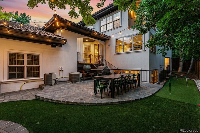 back house at dusk with central AC unit and a patio area