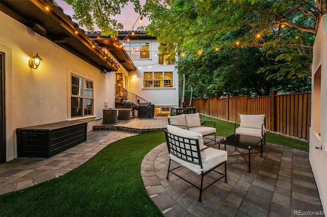 patio terrace at dusk featuring central air condition unit and an outdoor hangout area