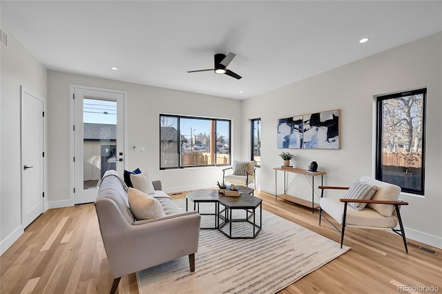 living room featuring recessed lighting, baseboards, and light wood finished floors