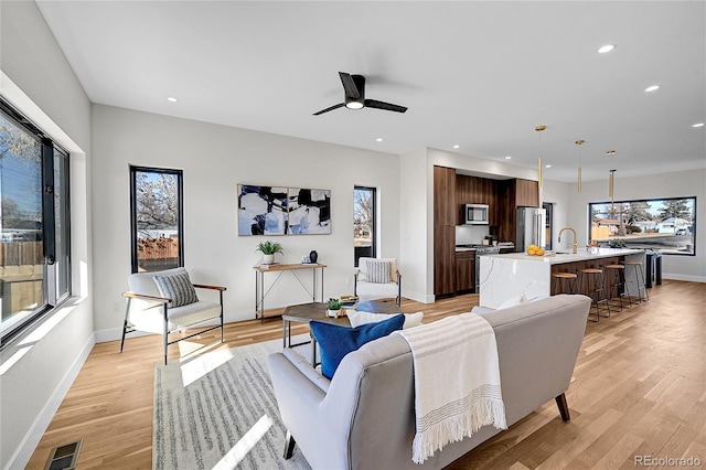 living room with recessed lighting, visible vents, light wood-style flooring, and baseboards