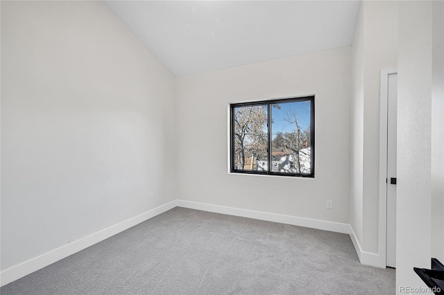 carpeted empty room with vaulted ceiling and baseboards