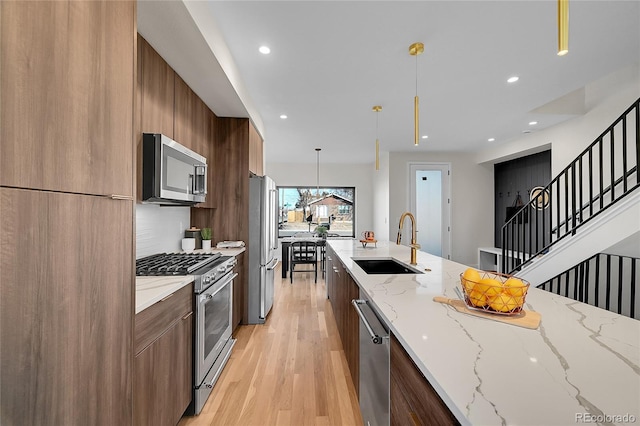 kitchen with light wood finished floors, recessed lighting, appliances with stainless steel finishes, a sink, and modern cabinets